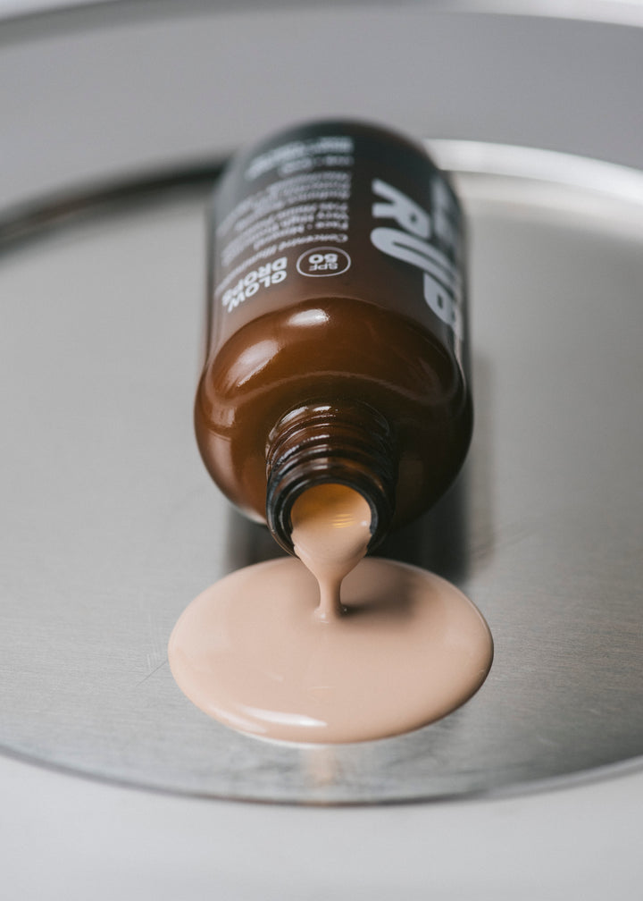Open bottle of Glow Drops SPF50 container with product spilling out.